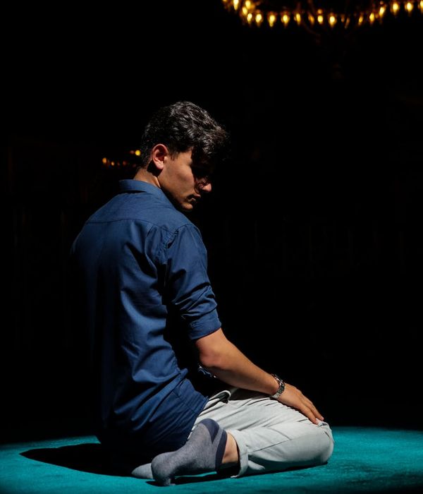 Man in a focused low-impact exercise pose in a dark room.